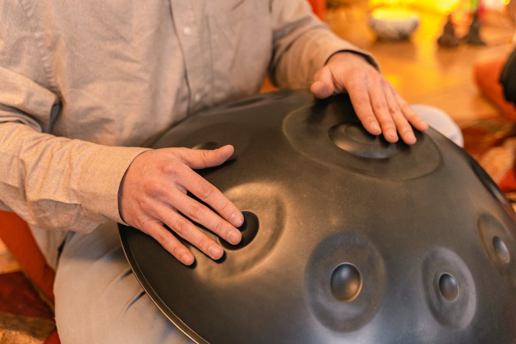 pexels photo 7970236 A person plays a handpan instrument, focusing on relaxation and zen vibes indoors.