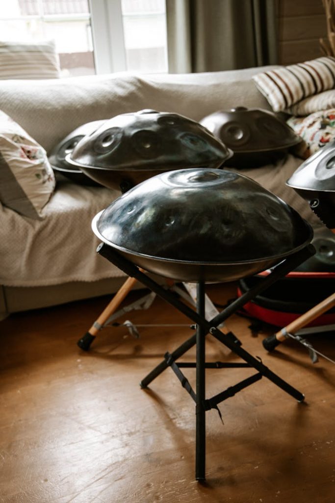 pexels photo 8355734 A set of handpans on stands in a cozy indoor setting with natural light streaming through a window.